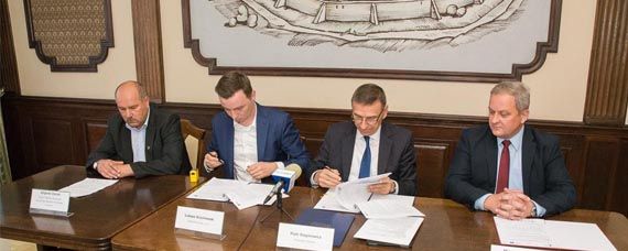 Prezydent Olsztyna podpisuje umowę. Obok prezydenta siedzą przedstawiciele urzędu marszałkowskiego