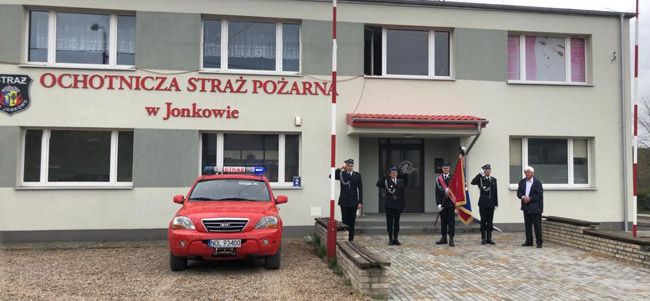 Poczet sztandarowy OSP Jonkowo przed budynkiem straży oddaje honory zmarłemu