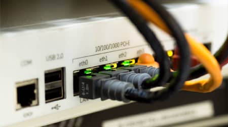 Zdjęcie urządzenia sieciowego z podłączonymi kablami ethernet.