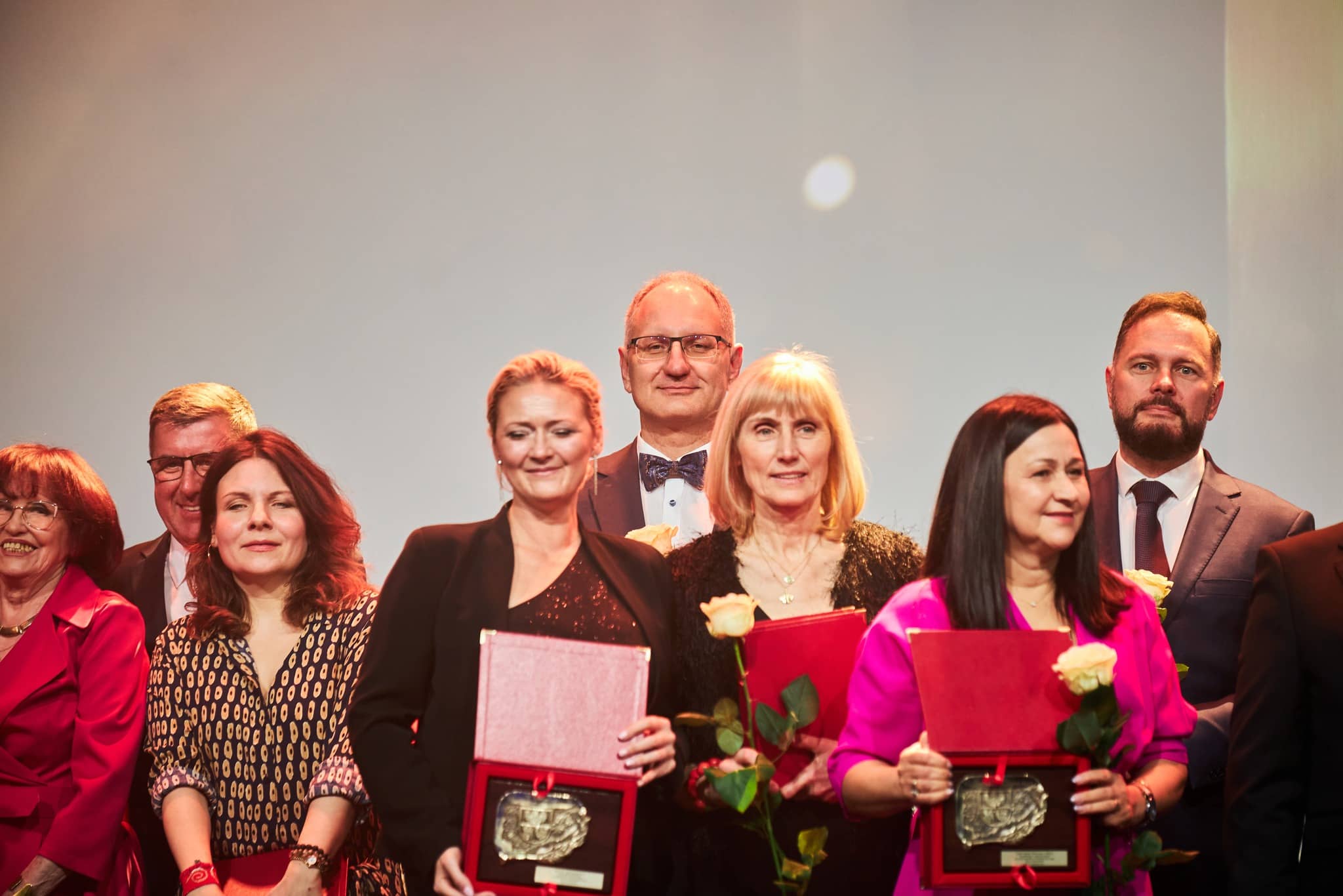Zdjęcie grupy osób prezentujących statuetki i wyróżnienia.