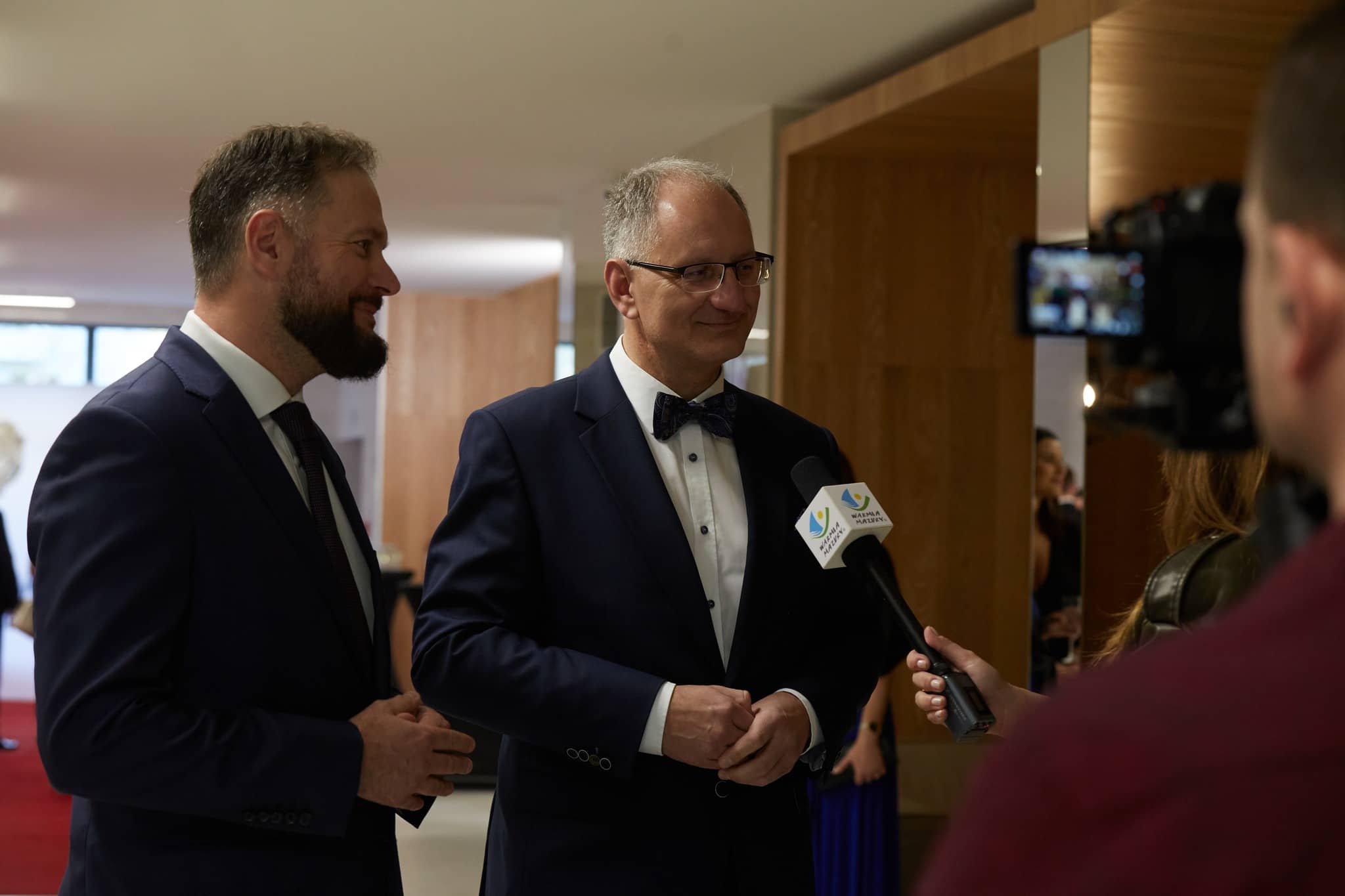 Dwóch mężczyzn udziela wywiadu telewizyjnego.