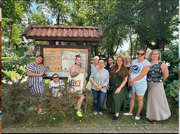 Grupa kobiet w plenerze przy tablicy informacyjnej